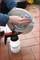 A person is cleaning a brake disc with a cloth. A spray bottle with cleaning fluid is positioned in front of it.