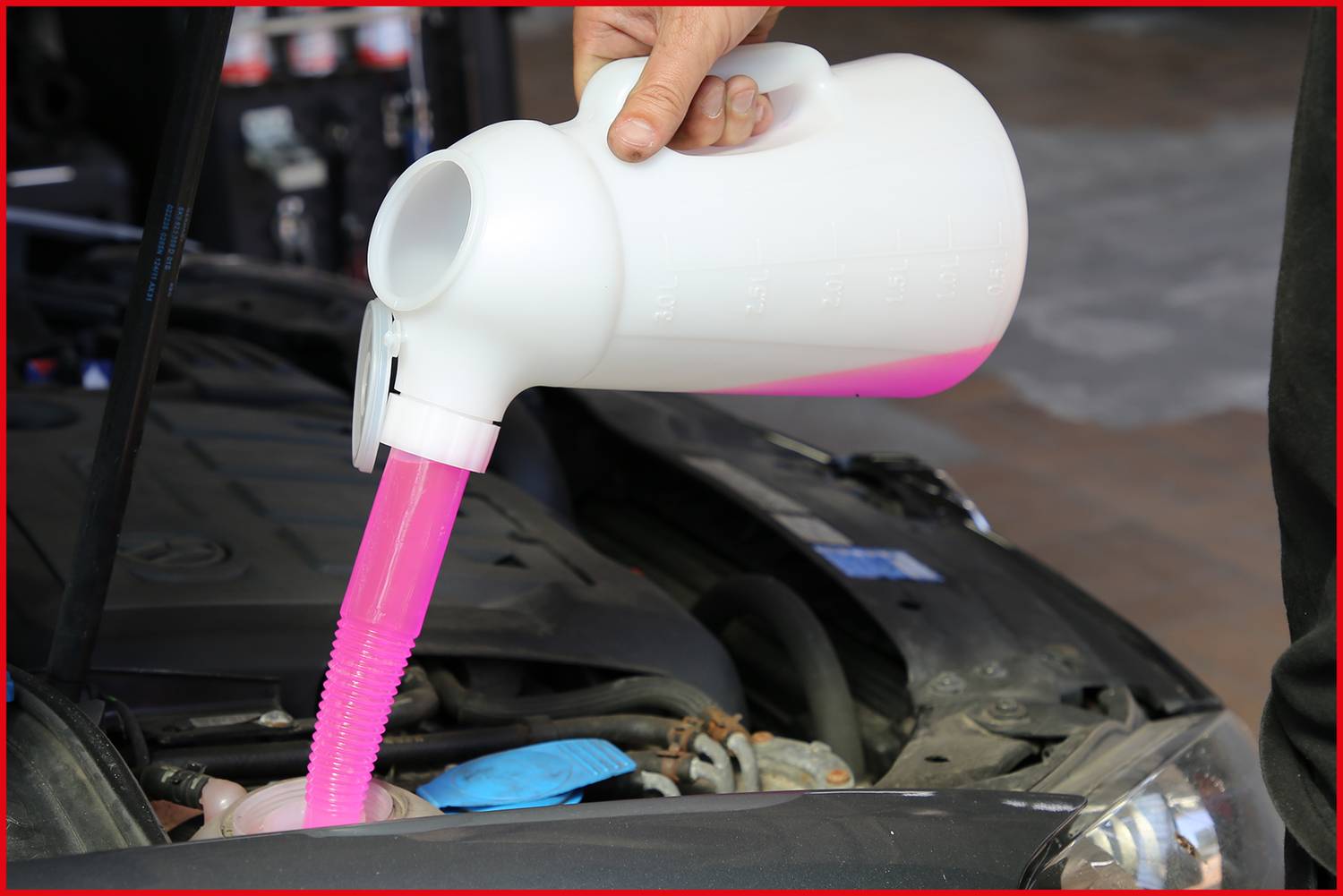 A person is pouring pink coolant into the engine bay of a car. On the left, the opened engine is visible.