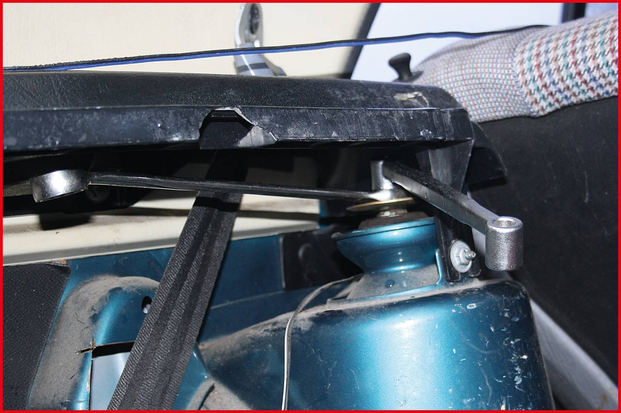 Close-up of a car seat, focusing on the mechanism for adjusting the backrest angle. A metal lever is visible.