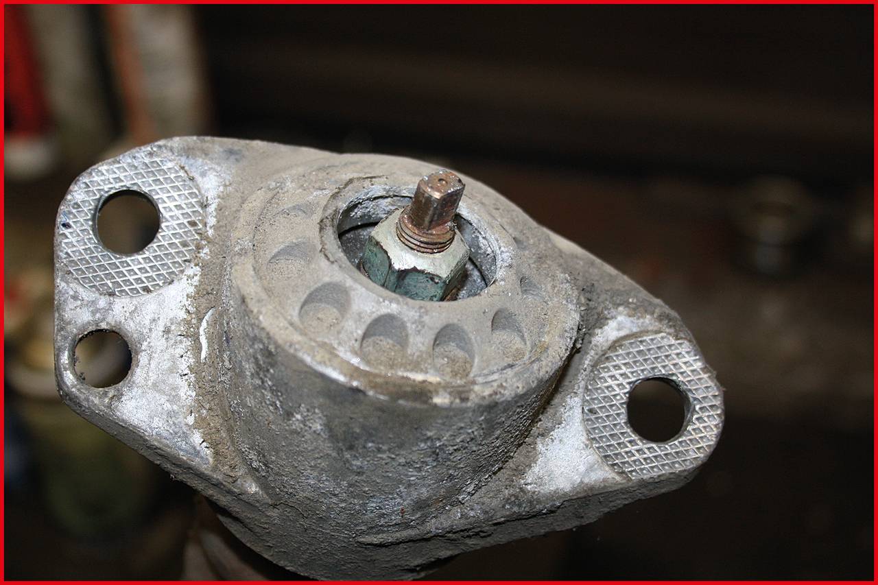 Close-up of a rusty metal bearing with anchor holes, likely part of a machine or vehicle.