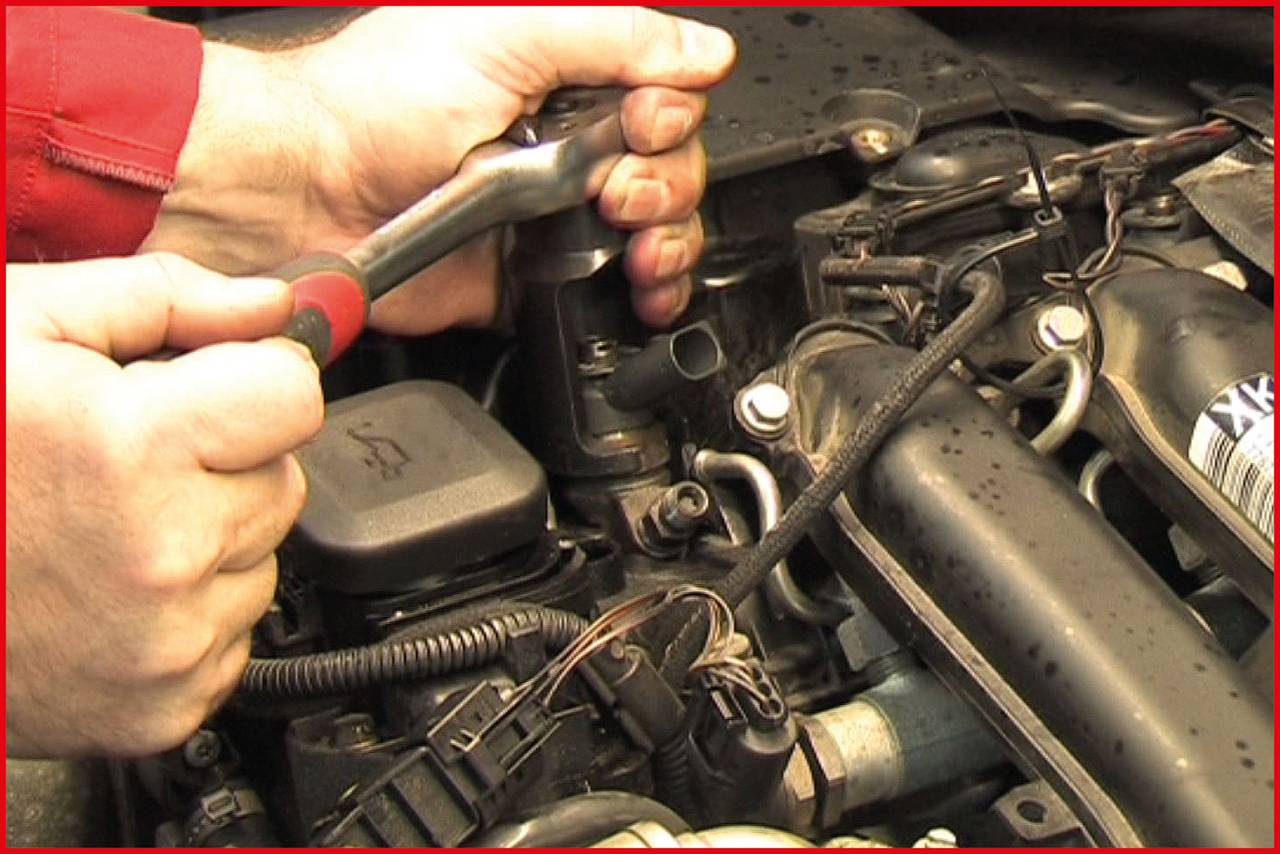 'Mechanic tightens screw in car engine compartment.'