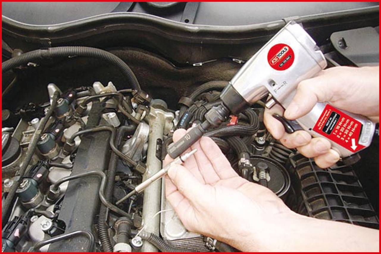 A person is using an electric drill to tighten screws in the engine compartment of a car.