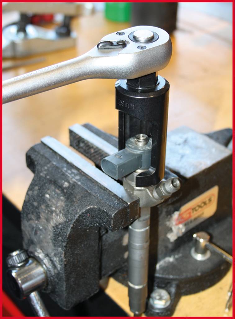 A ratchet is used to work a screw thread in a vice. The background shows a workbench.