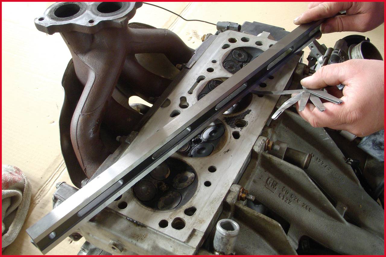'A person is checking the cylinder head of an engine with a measuring tool, with the engine block partially assembled.'