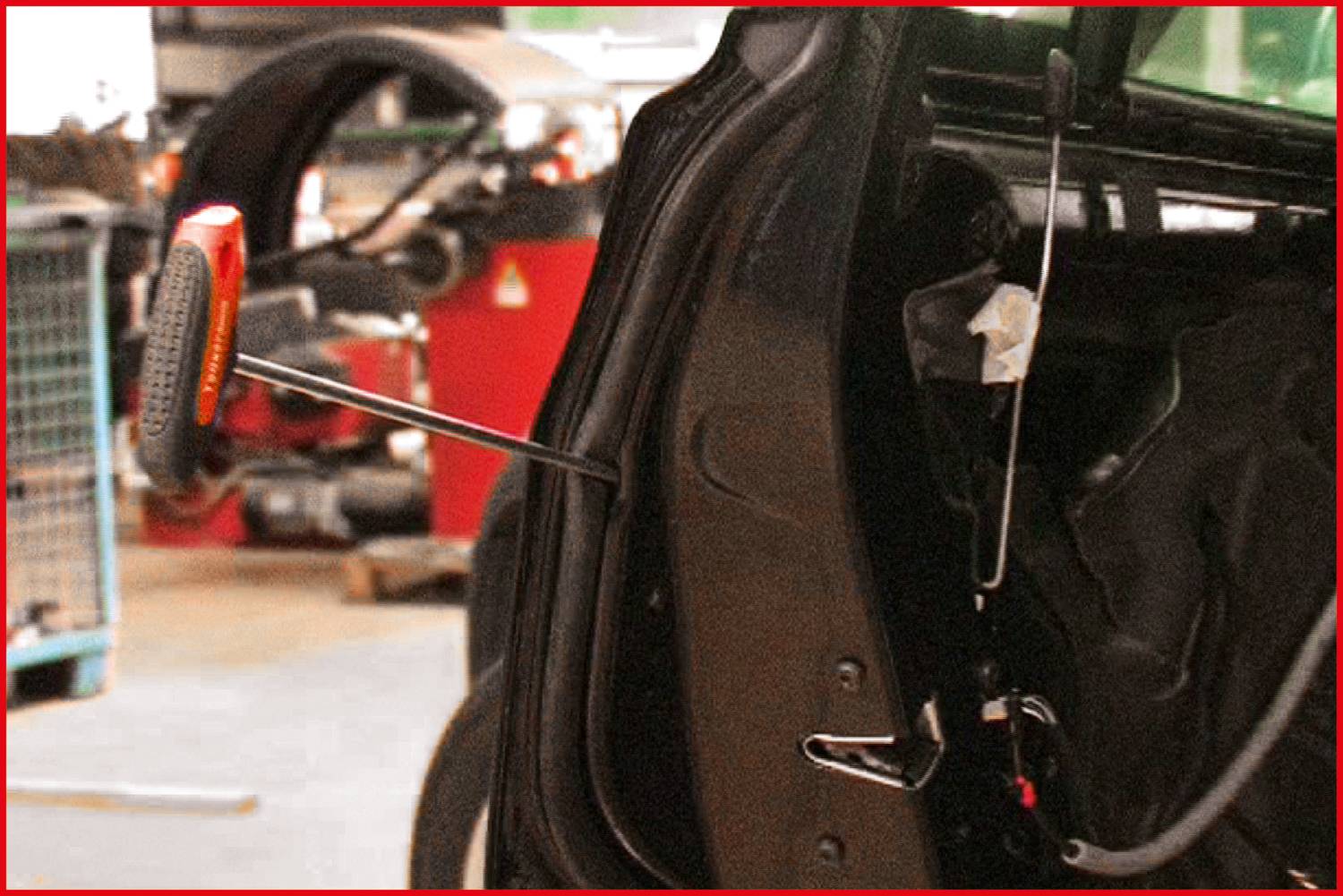 A car in a garage workshop, door open, repair tools visible. People in the background. Focus on the door and the tools.