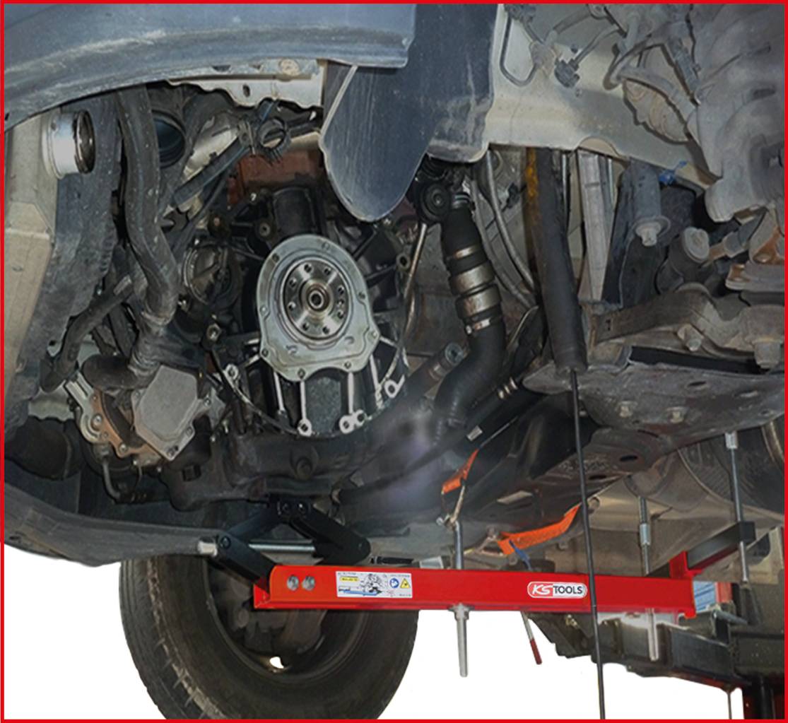 A car viewed from underneath, reveals the exposed gearbox and various mechanical components during a repair phase.