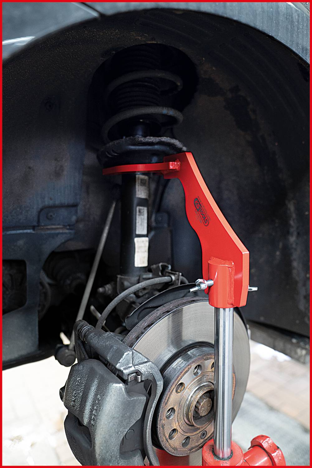 Car suspension strut with spring and brake disc in close-up, showing the interaction of components in a vehicle suspension system.