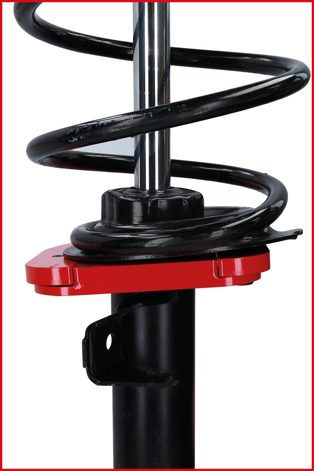 Close-up of a shock absorber with a coil spring, mounted on a black metal cylinder. Red mounting bracket around the base of the spring.