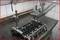 A workshop shows an engine block on a table, secured by a clamping device for repair work.