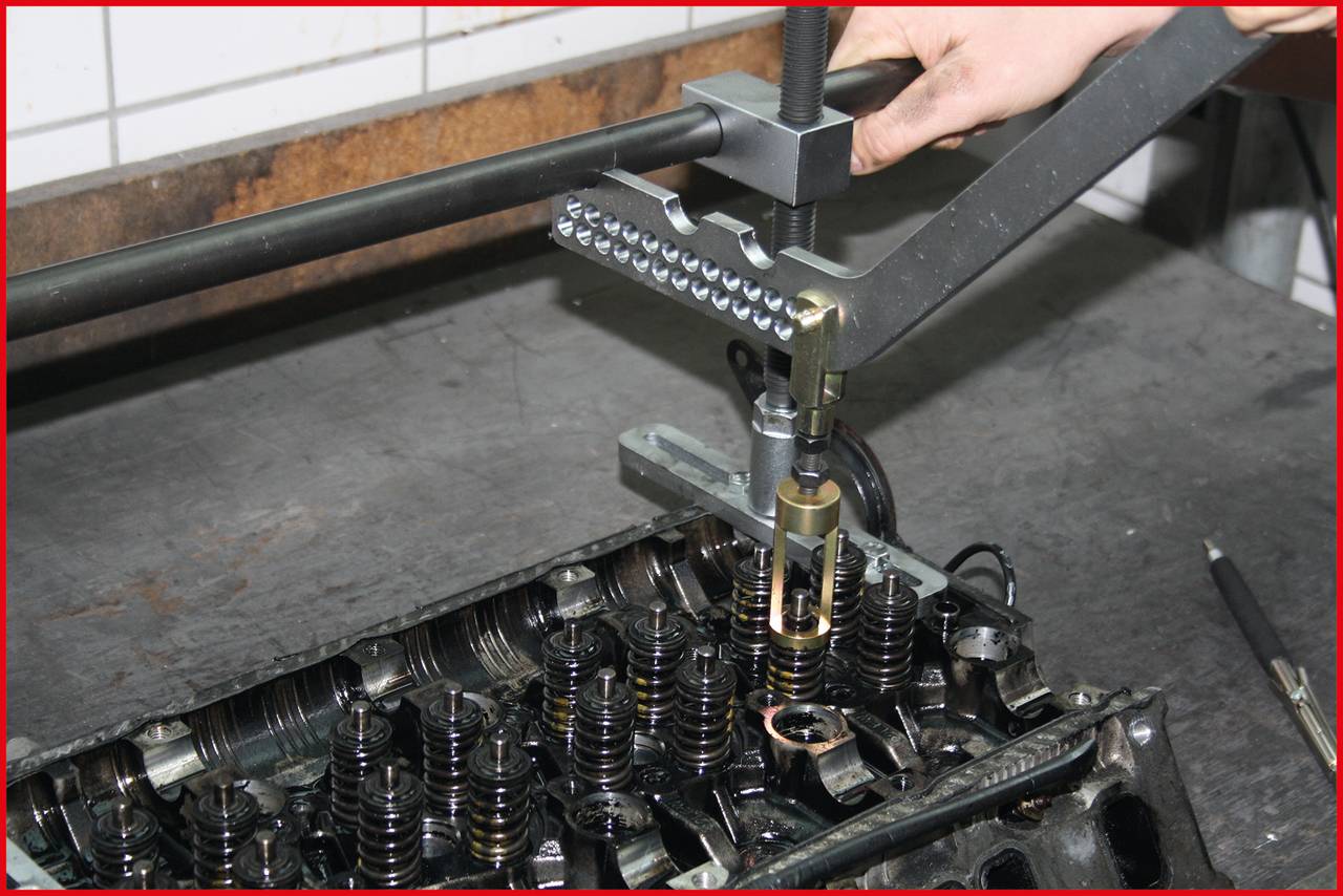A mechanic is using a specialised tool to measure the valve clearance on an engine. The engine is partially dismantled.