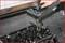 A mechanic is using a specialised tool to measure the valve clearance on an engine. The engine is partially dismantled.