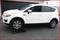 A white car is partially positioned on a ramp, which raises the front right wheel. It is situated on a paved surface.