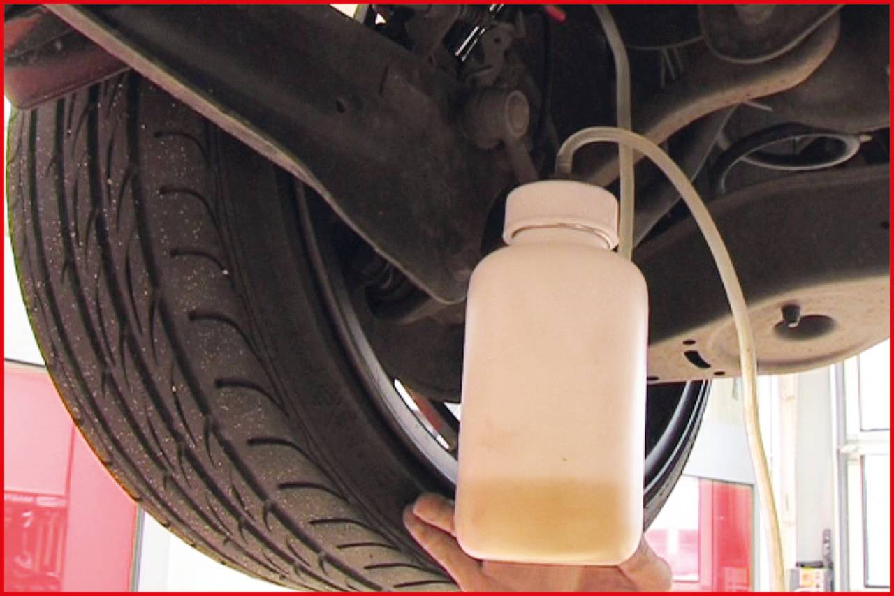 Car tyres in a garage, brake fluid being drained from the system into a white container.