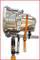 'Transmission in silver colour, secured with an orange strap and mounted on a hydraulic lifting device.'