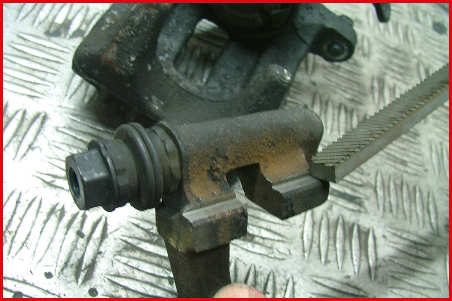 Brake calliper filed down. Detailed view on a structured metal floor. Vehicle parts repair and maintenance.