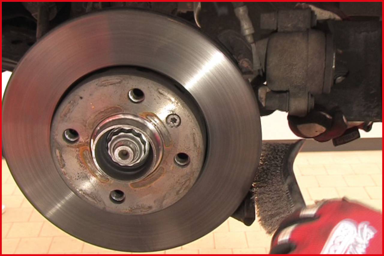 Close-up of a brake disc in a vehicle, with a hand seemingly performing cleaning or maintenance.