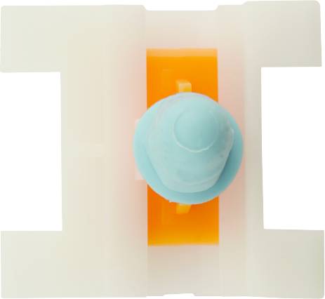 A white plastic holder with an orange and blue insert in the centre. The component could be part of a larger mechanical system.