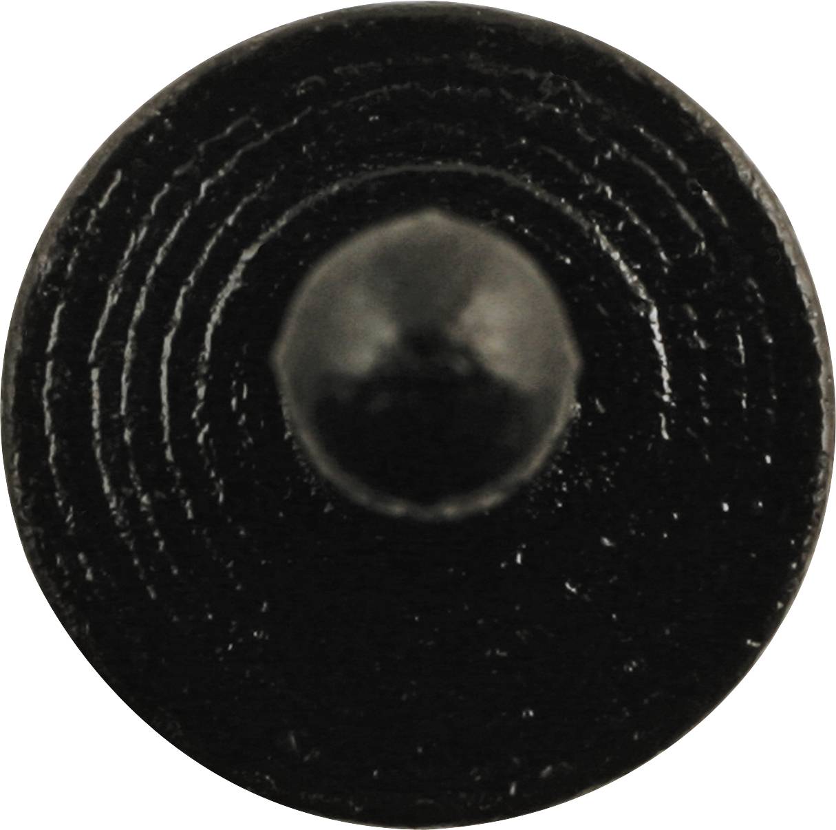 Close-up of a black, round nail head with concentric circles.