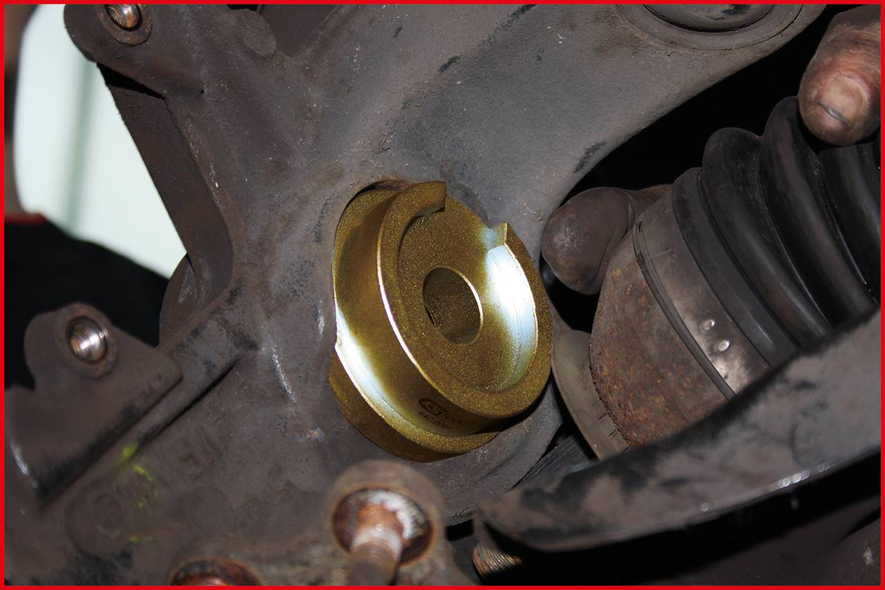A mechanic is showing a built-in car part that is secured in a suspension mount.