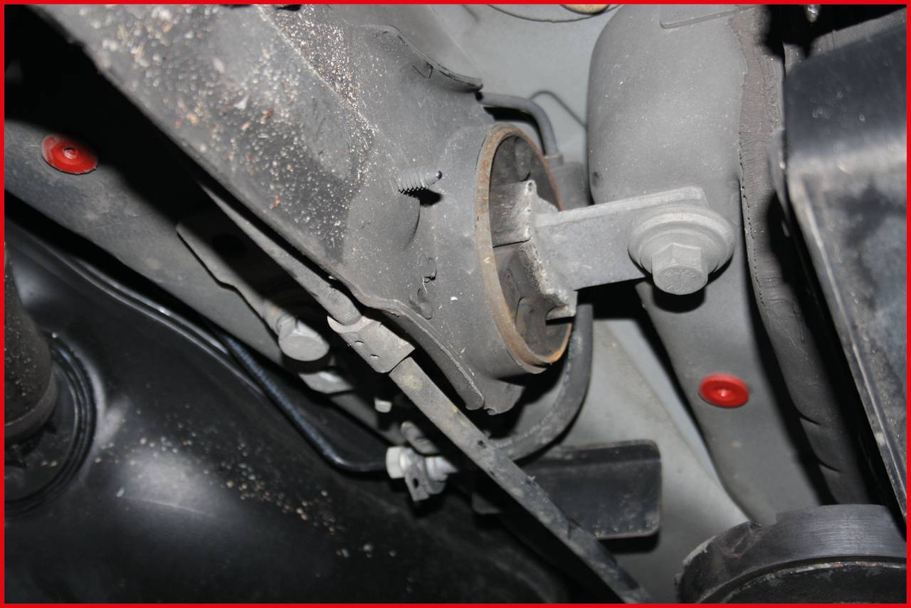 Vehicle underside with a close-up of the suspension. Parts of the suspension and mounting components are visible.