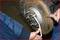 A person is changing a car brake system, using a spanner to loosen a screw on the brake disc.