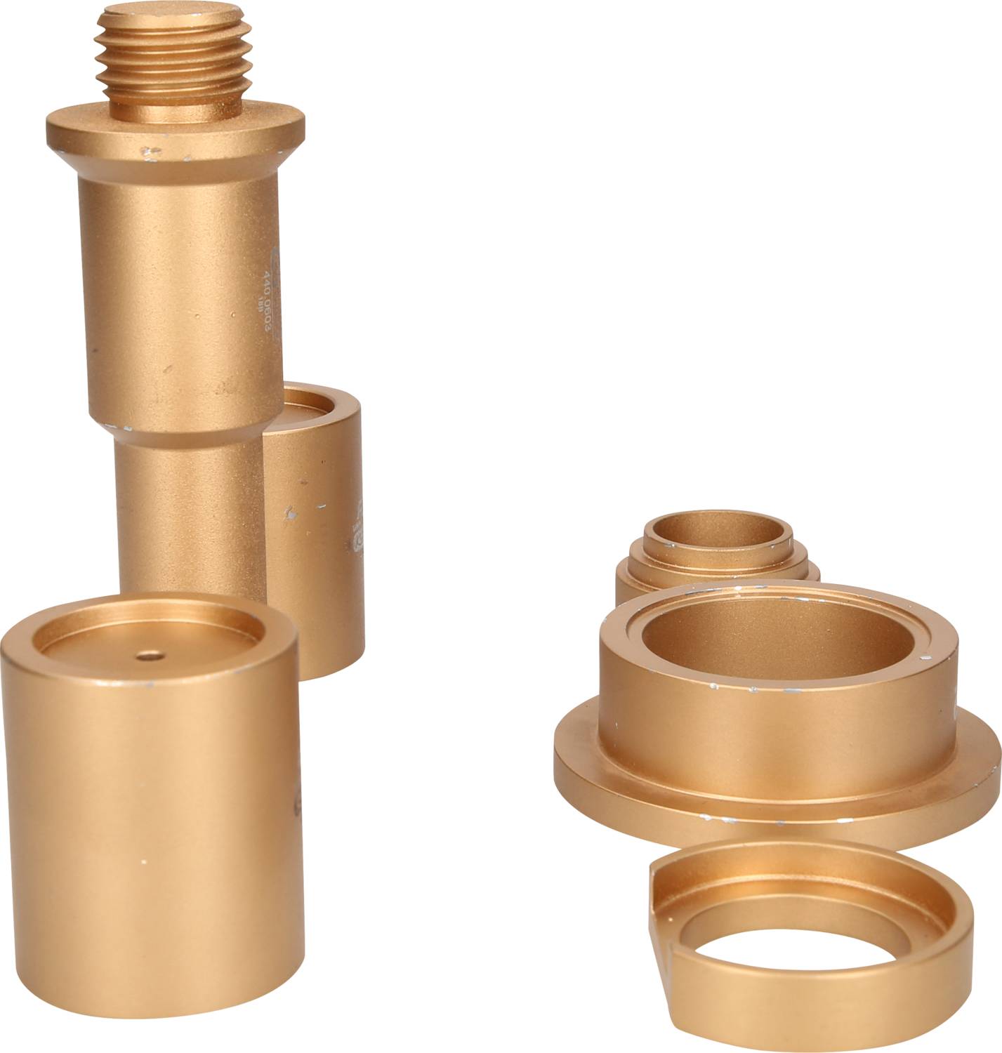 Two gold-coloured metal components, consisting of multiple cylinders and rings, positioned side by side on a white background.