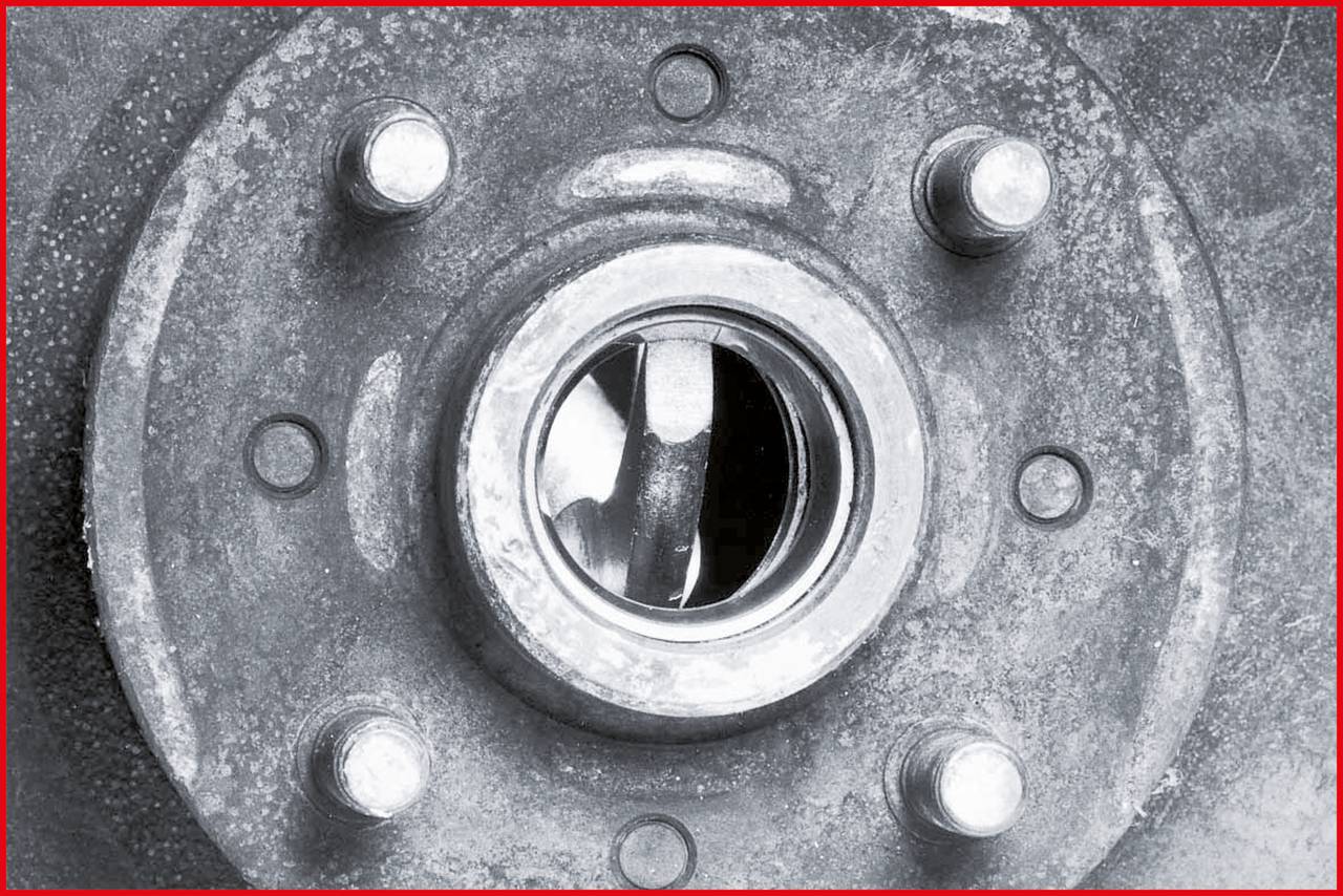 Close-up of a metal flange with a central hole and screws arranged in a circular pattern.