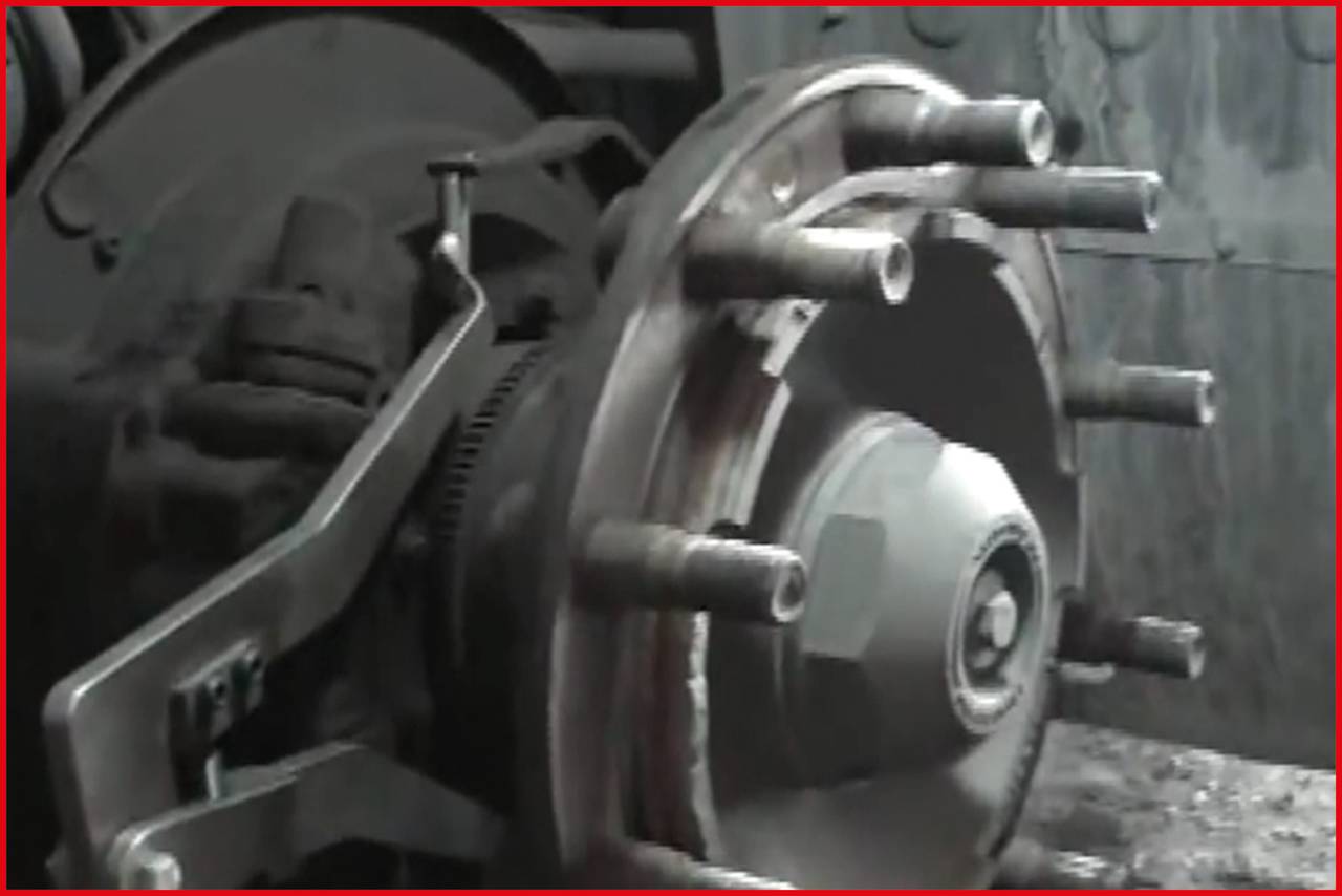 Close-up of a vehicle braking system, comprising a brake disc, brake calliper, and wheel bolt. The image reveals details of the metal mechanics.