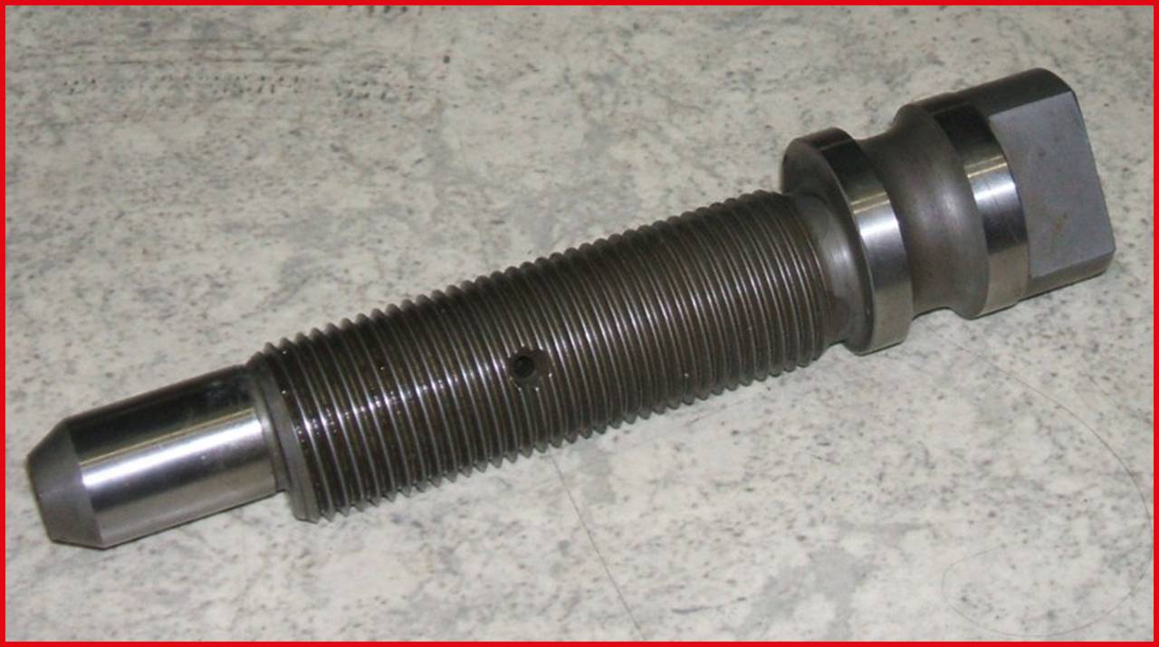 Metallic threaded bolt with a cylindrical body and hexagonal head on a grey surface.