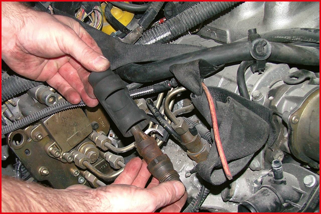 'Hands working on a car ignition system, holding a spark plug. Cables and engine components are visible in the background.'