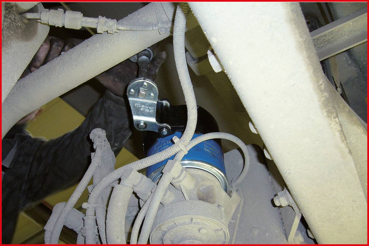 'Mechanic installs fuel filter underneath a vehicle.'