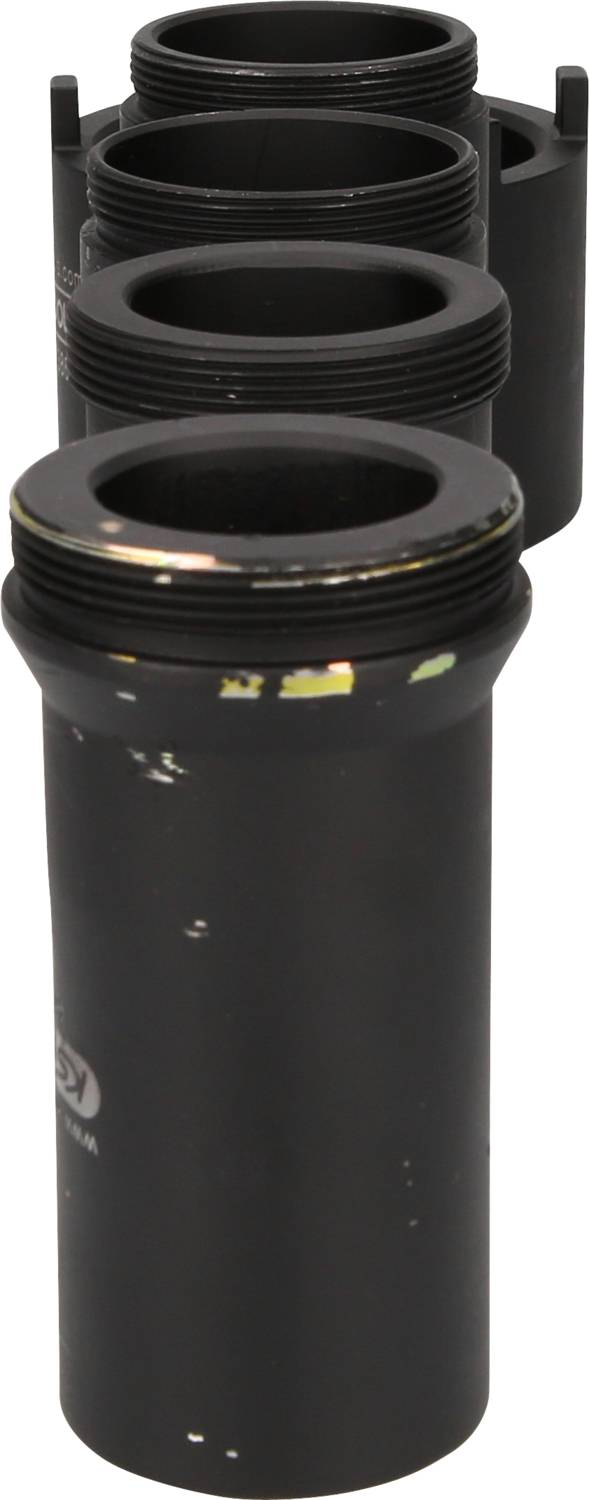 Four black, cylindrical adapter rings are stacked one behind another, of varying sizes, and show slight signs of wear.