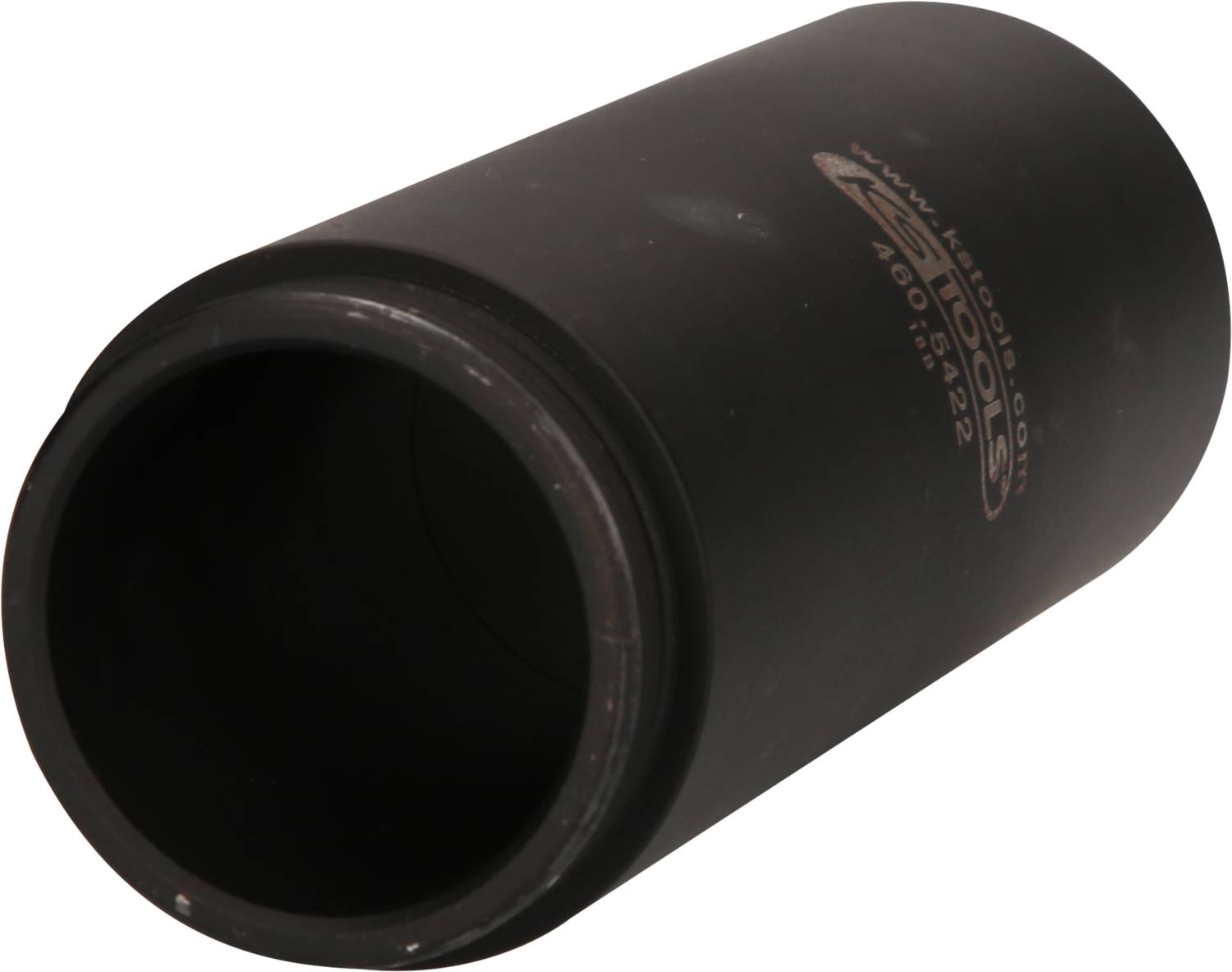 A black cylinder, possibly a tool component, is lying on its side. A web address is printed on its surface.