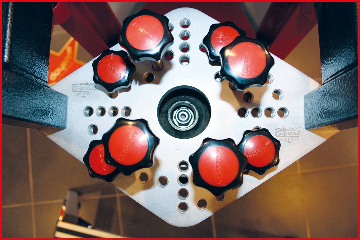 Tool with eight red rotary handles on a silver platform; top-down view. Tool likely for precision or adjustment purposes.