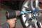 'A person is using an impact driver to remove or tighten the wheel nuts of a car tyre.'