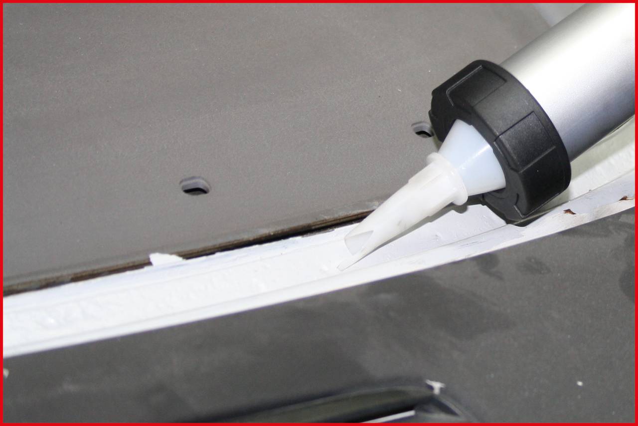 A cartridge gun applies a white sealant to a gap between two surfaces to seal it.