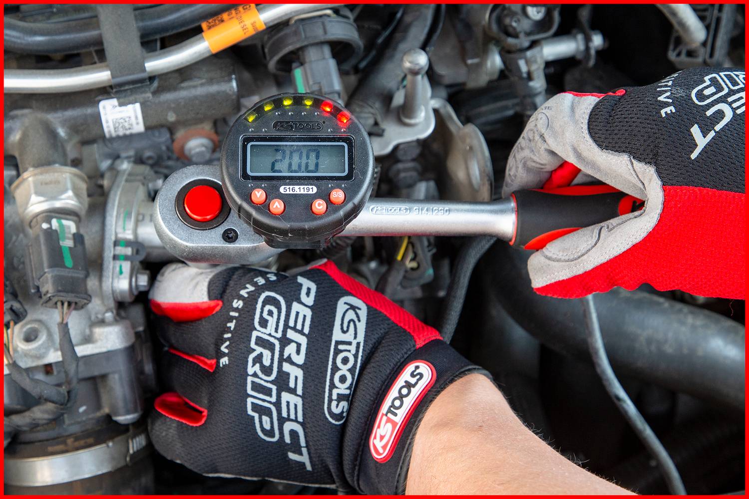 'A person wearing red gloves is using a digital torque wrench displaying 200, to tighten a screw in the engine compartment.'