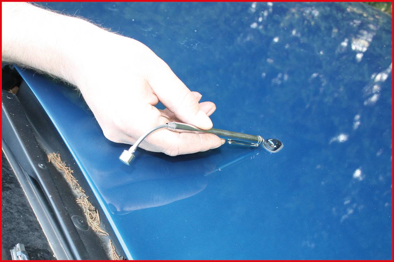 A hand is using a pressure gauge on a vehicle tyre valve. This measures the tyre pressure for maintenance purposes.
