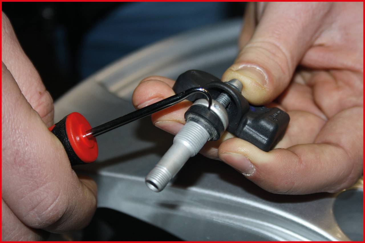 Close-up of hands adjusting a valve on a tyre with a spanner.