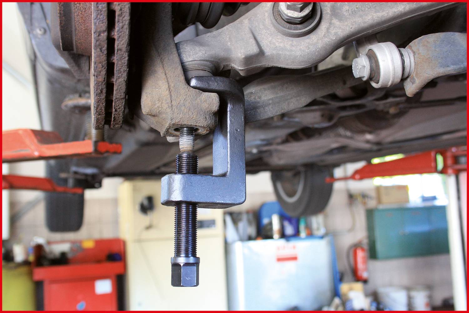 A ball joint puller is used to remove a ball joint from a vehicle. The image shows its use in a workshop.