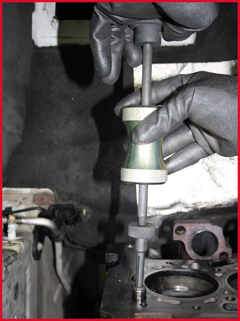A person wearing gloves is measuring the depth of a hole in a metal part using a depth gauge in a workshop.