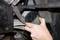 A hand holds a green oil filter during replacement in a vehicle's engine compartment.