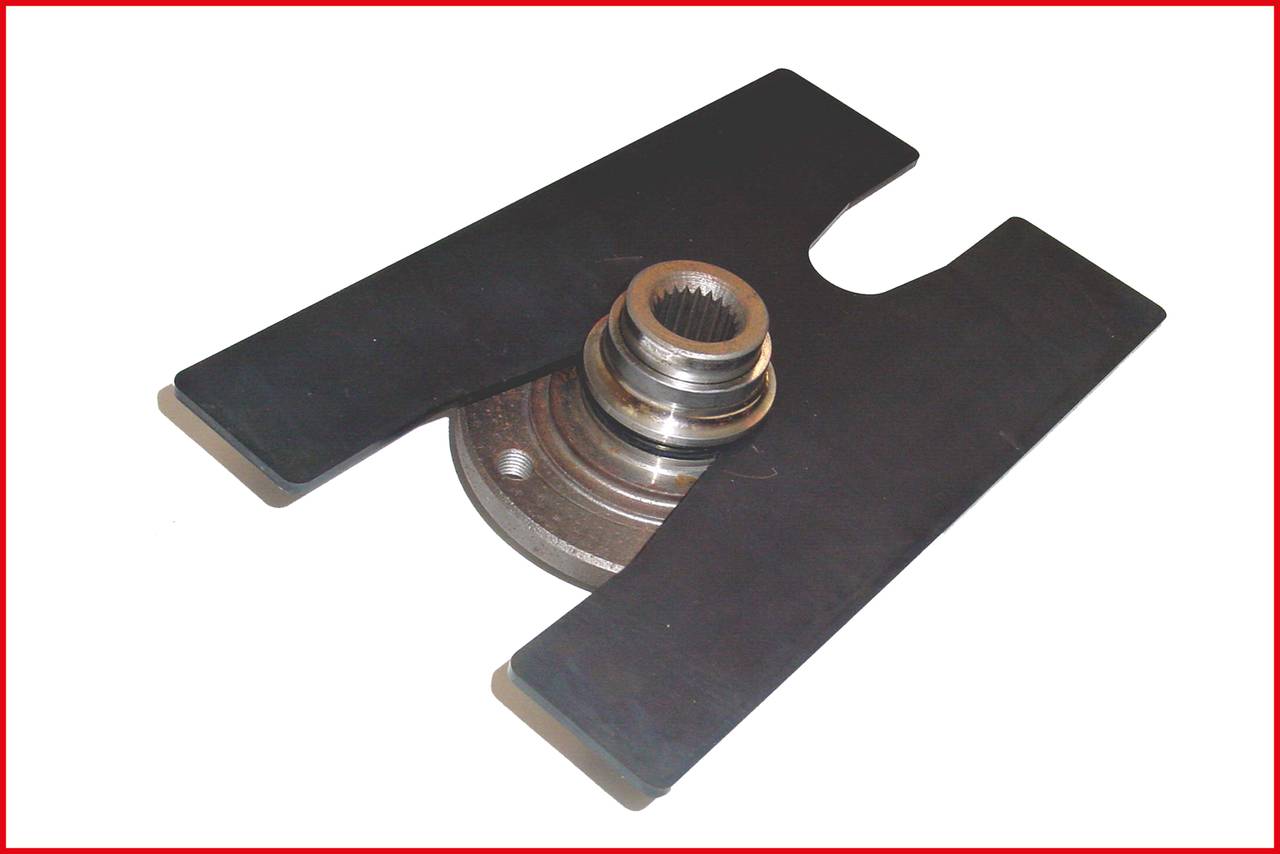 A metallic machine part lies on a flat, black surface. It has a central shaft with toothed edges.