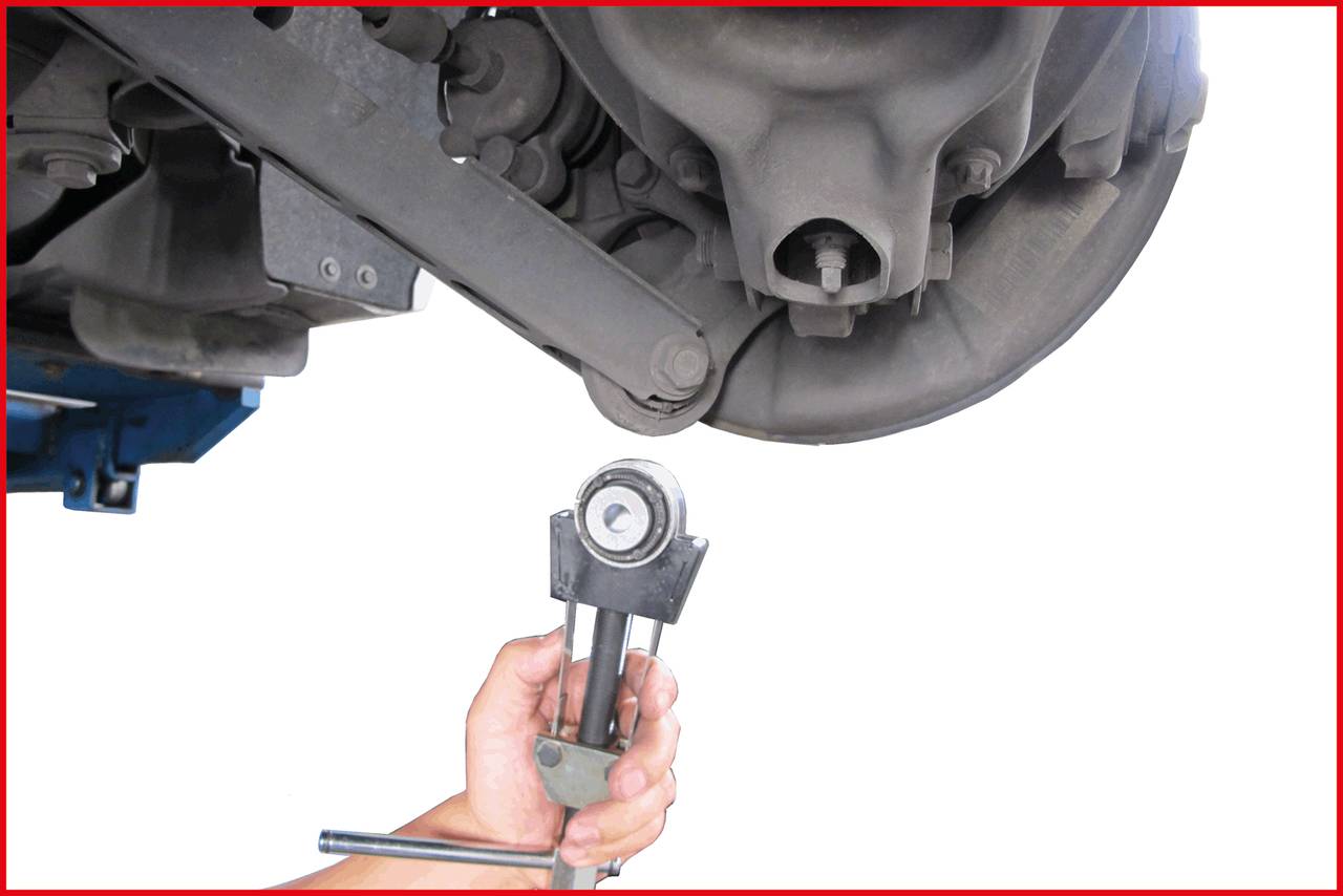 A person is holding a tool while working on the rear axle of a car.