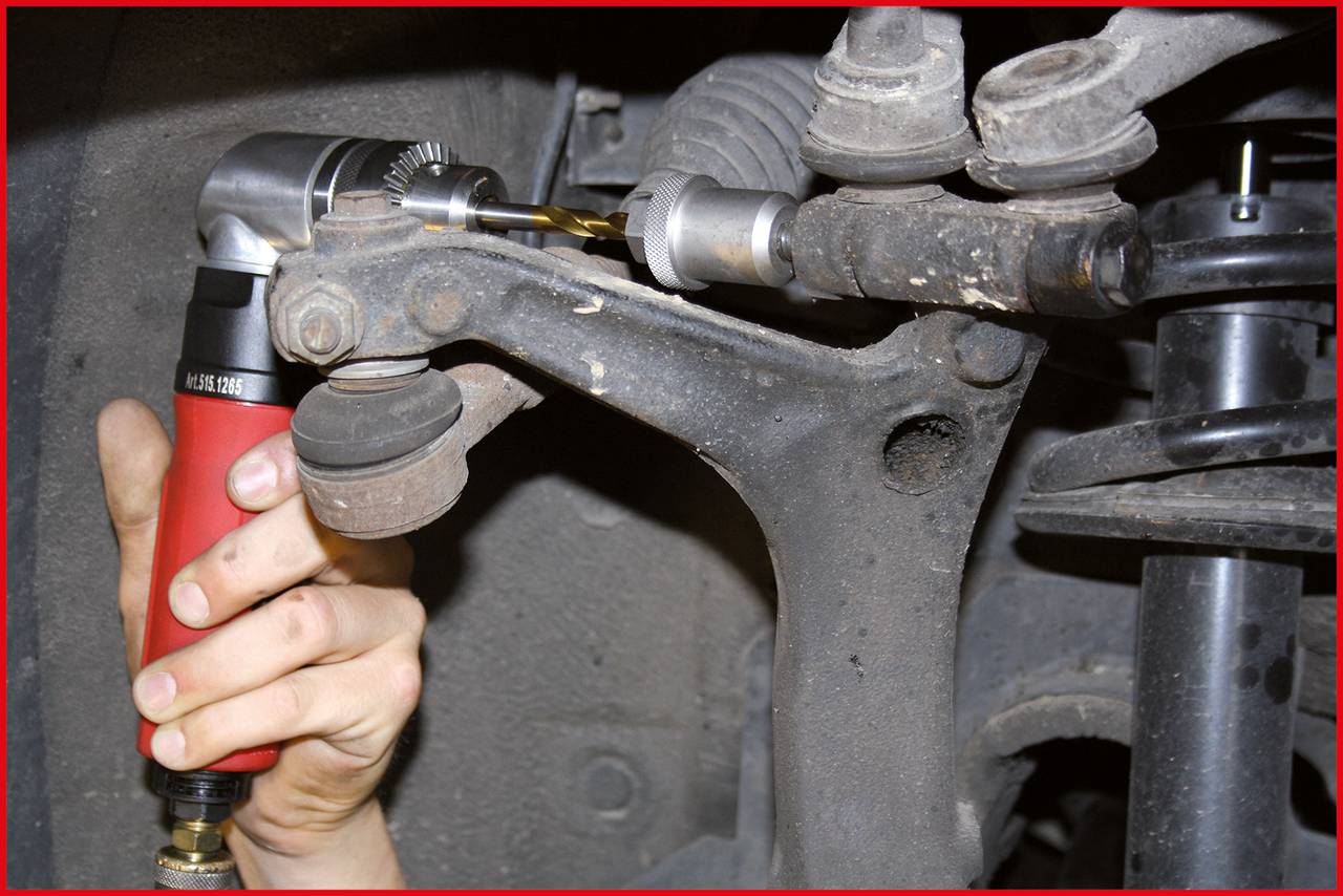 A person is using a machine to remove a worn steering linkage from a vehicle. Clear view of the mechanical process.