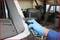 A person wearing blue gloves is cutting adhesive on a car windscreen in a workshop.