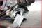 A rusted car part lies on a workbench, a tool with the inscription 'TOOLS' is being used to remove deposits.