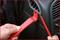 A person is using red plastic tools to remove a car's interior trim.