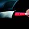 A hand holds a knife with a red blade against a dark background.