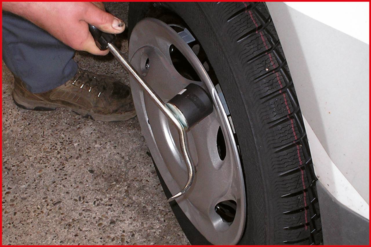 A person is tightening the wheel nuts of a car with a wheel brace. Close-up of the wheel and tool usage.